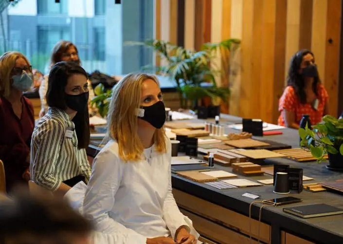 Asistentes con mascarilla sentados alrededor de la mesa de materiales durante la mesa redonda.