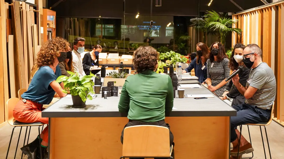 Participantes con mascarilla sentados alrededor de una gran mesa con plantas en Matter Barcelona