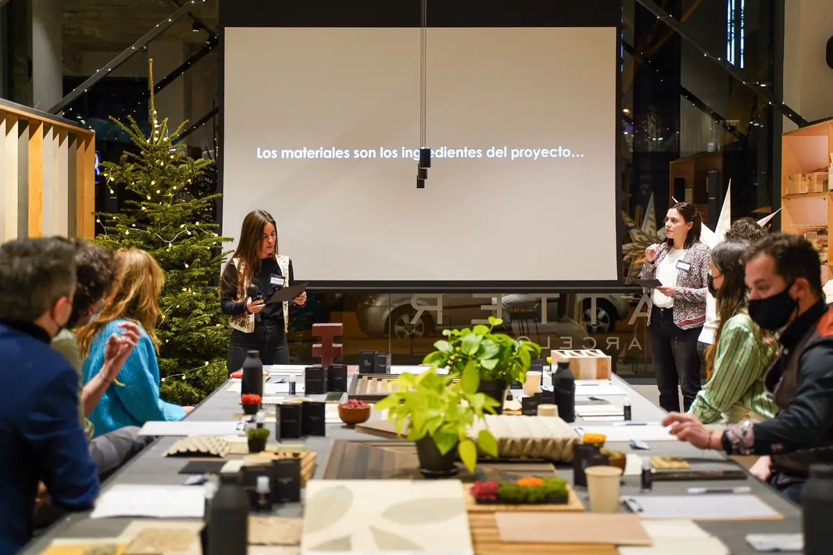 Presentación de Matter Atelier ante los asistentes sentados alrededor de una mesa con muestras de materiales