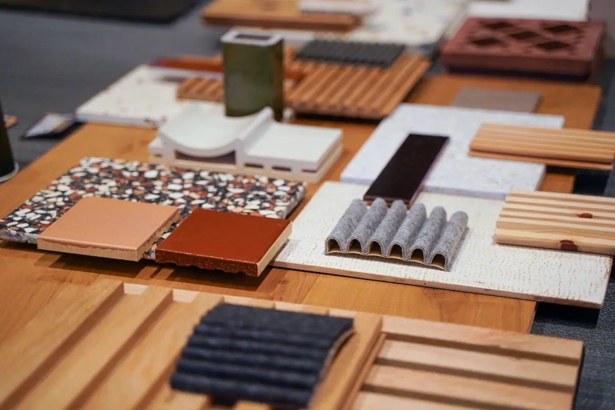 Muestras de terrazo, cerámica esmaltada, listones de madera y fieltro sobre una mesa de madera