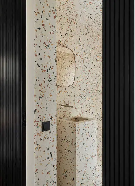 Aseo revestido de terrazo blanco con grano de colores y lavabo exento del mismo material