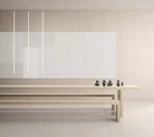 Sala diáfana con paneles acústicos claros en la pared y una mesa con bancos de madera
