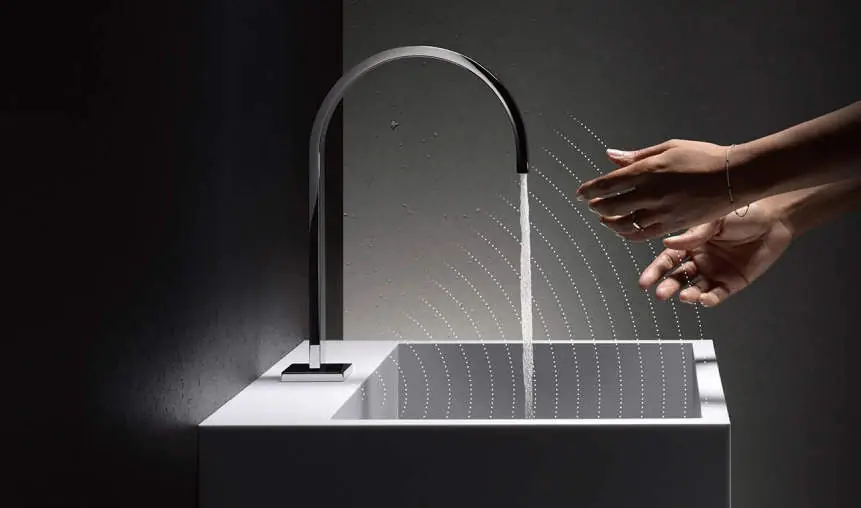 Lavabo blanco con grifo de caño curvo y unas manos bajo el chorro de agua