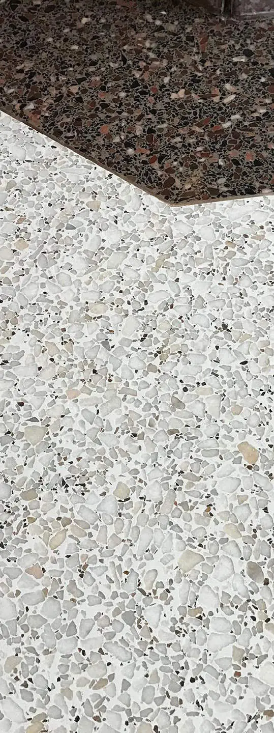 Detalle de pavimento de terrazo continuo con grano claro junto a una franja de grano oscuro