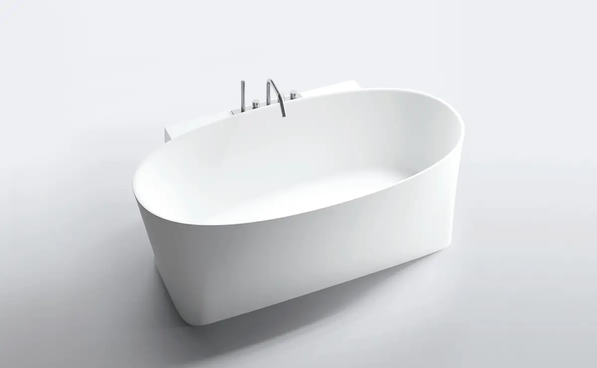 Bañera exenta blanca de forma ovalada con la grifería montada en un volumen posterior.