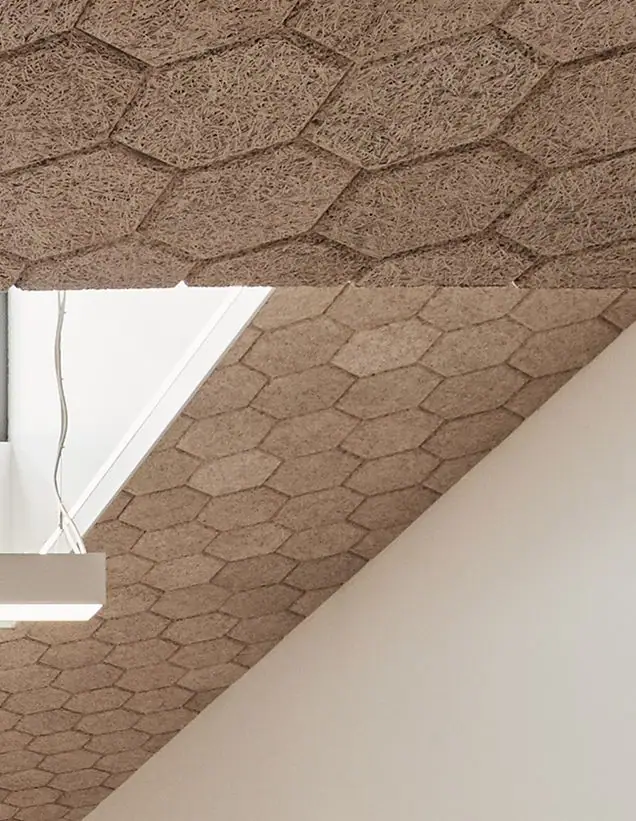 Techo inclinado revestido con baldosas acústicas hexagonales de lana de madera en tono natural