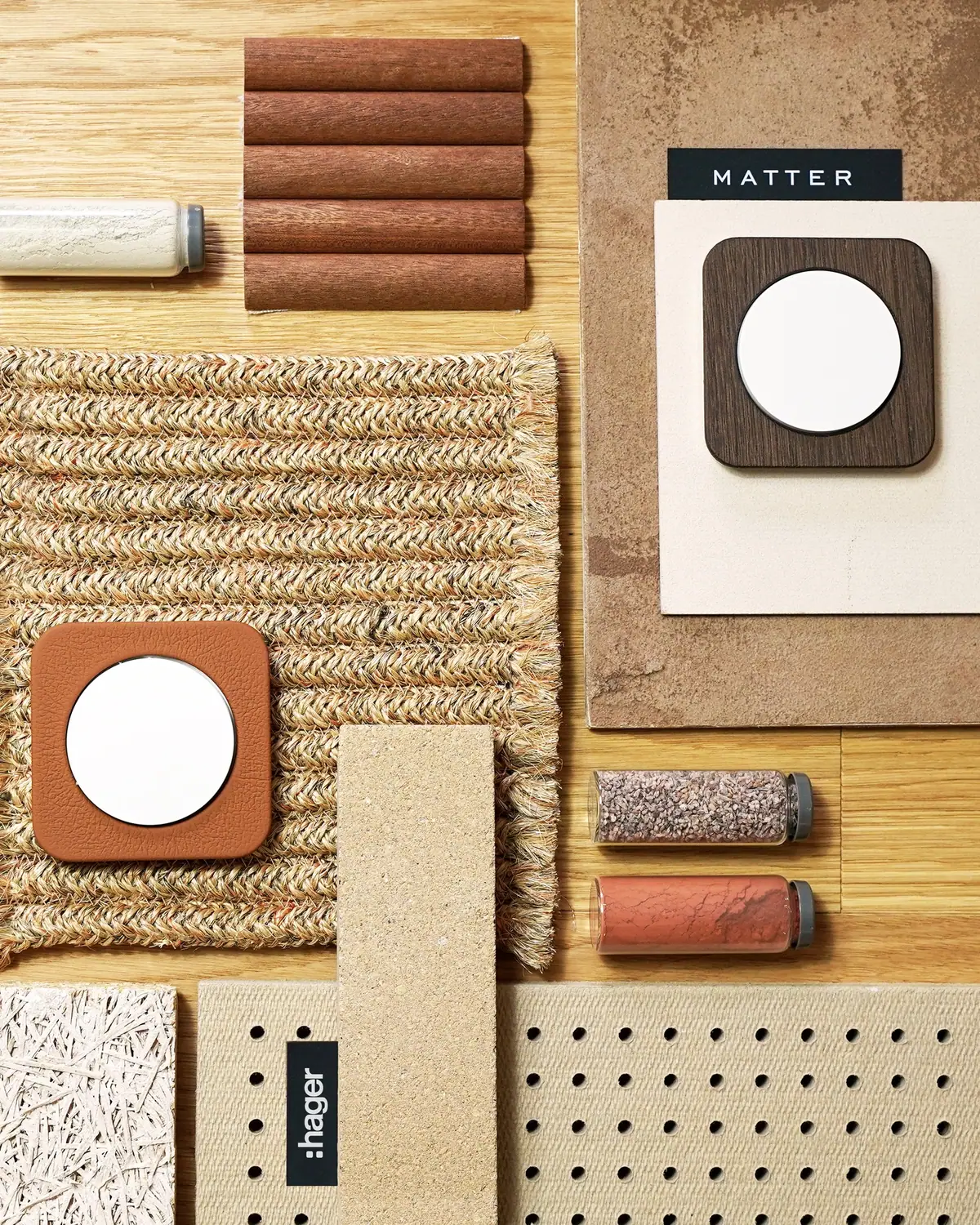 Composición de materiales con dos mecanismos Berker R.1, uno con marco de piel marrón y otro con marco de madera, sobre sisal, madera y cerámica