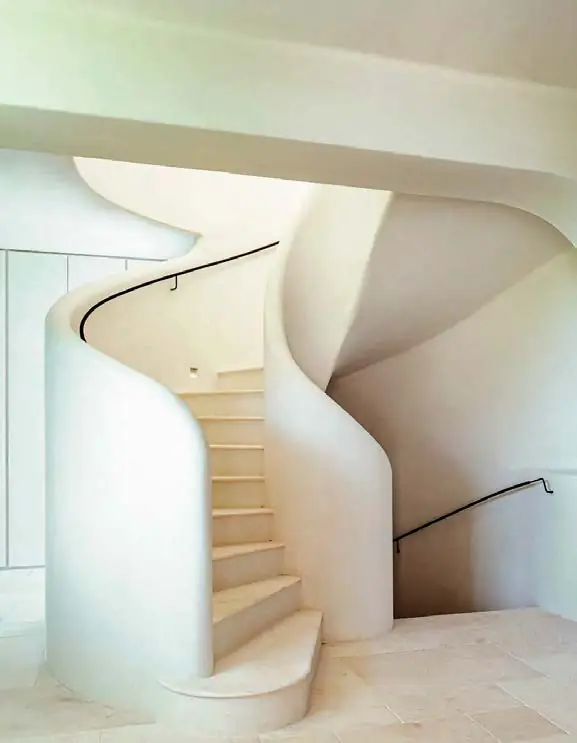 Escalera helicoidal blanca de formas curvas con revestimiento continuo y peldaños claros