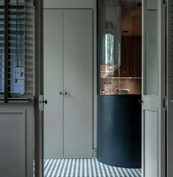 Puertas de madera con contraventanas abiertas hacia un baño con pavimento de damero blanco y negro