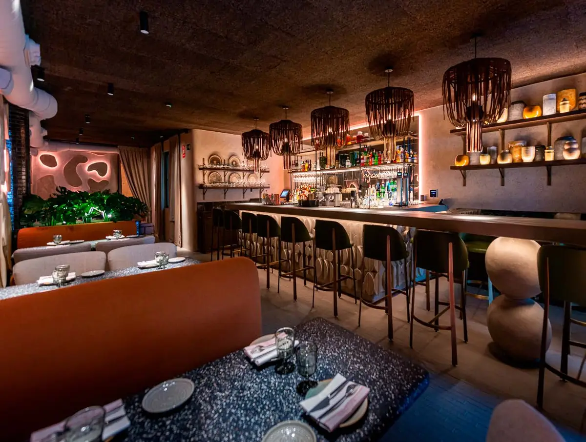 Interior del restaurante Terracotta con barra iluminada, lámparas de fibra y paredes de tonos tierra
