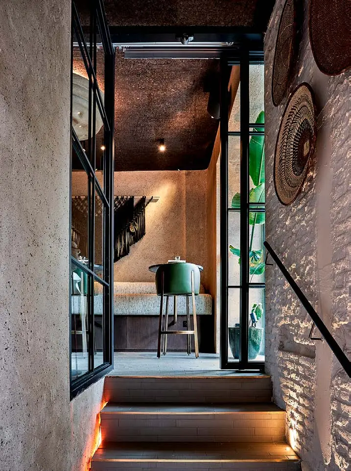 Escalera con pared de ladrillo, nichos con vasijas de barro y platos artesanales iluminados con luz cálida