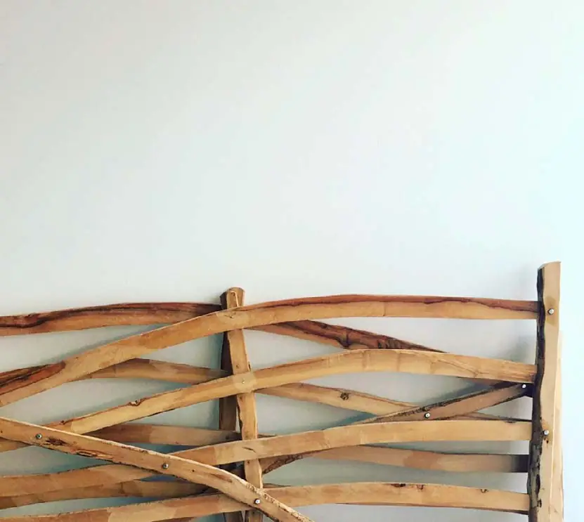 Pieza de madera de ramas de olivo ensambladas sobre una pared blanca