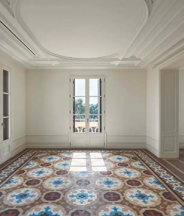 Sala rehabilitada con molduras blancas y un pavimento de mosaico Nolla en tonos azules y rojizos