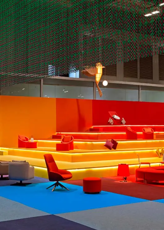 Graderío naranja y rojo bajo una cortina de cadenas metálicas de colores en la sala VIP de ARCO