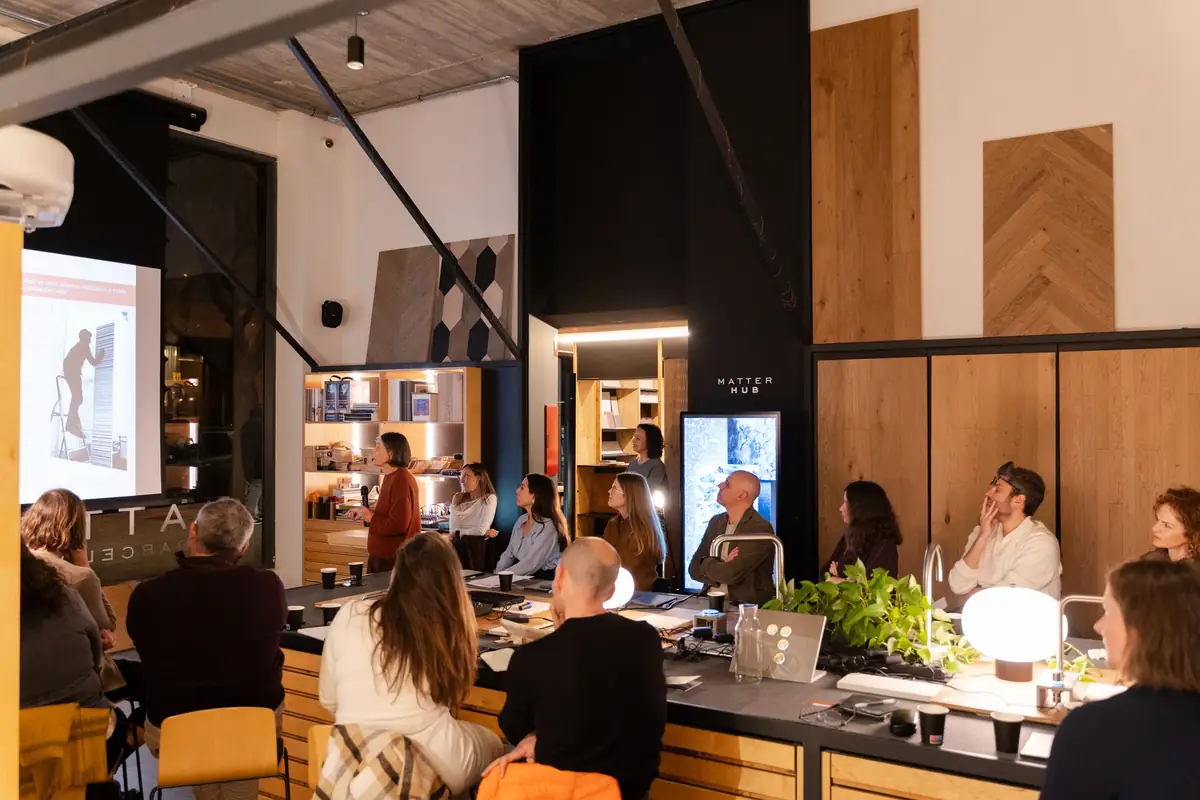 Ponente presentando ante los asistentes junto a una pantalla con una imagen de obra