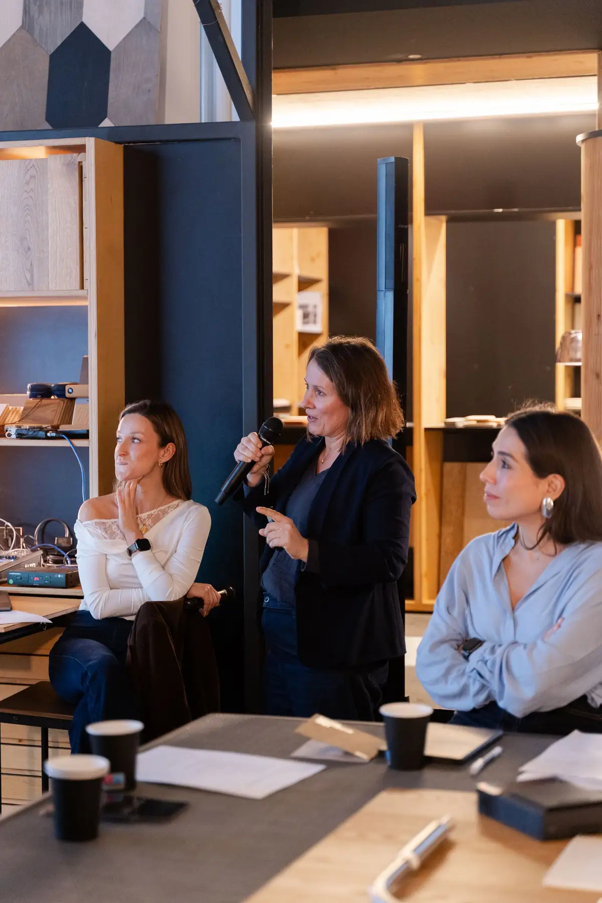 Tres ponentes conversan sentadas a la mesa, una de ellas con micrófono