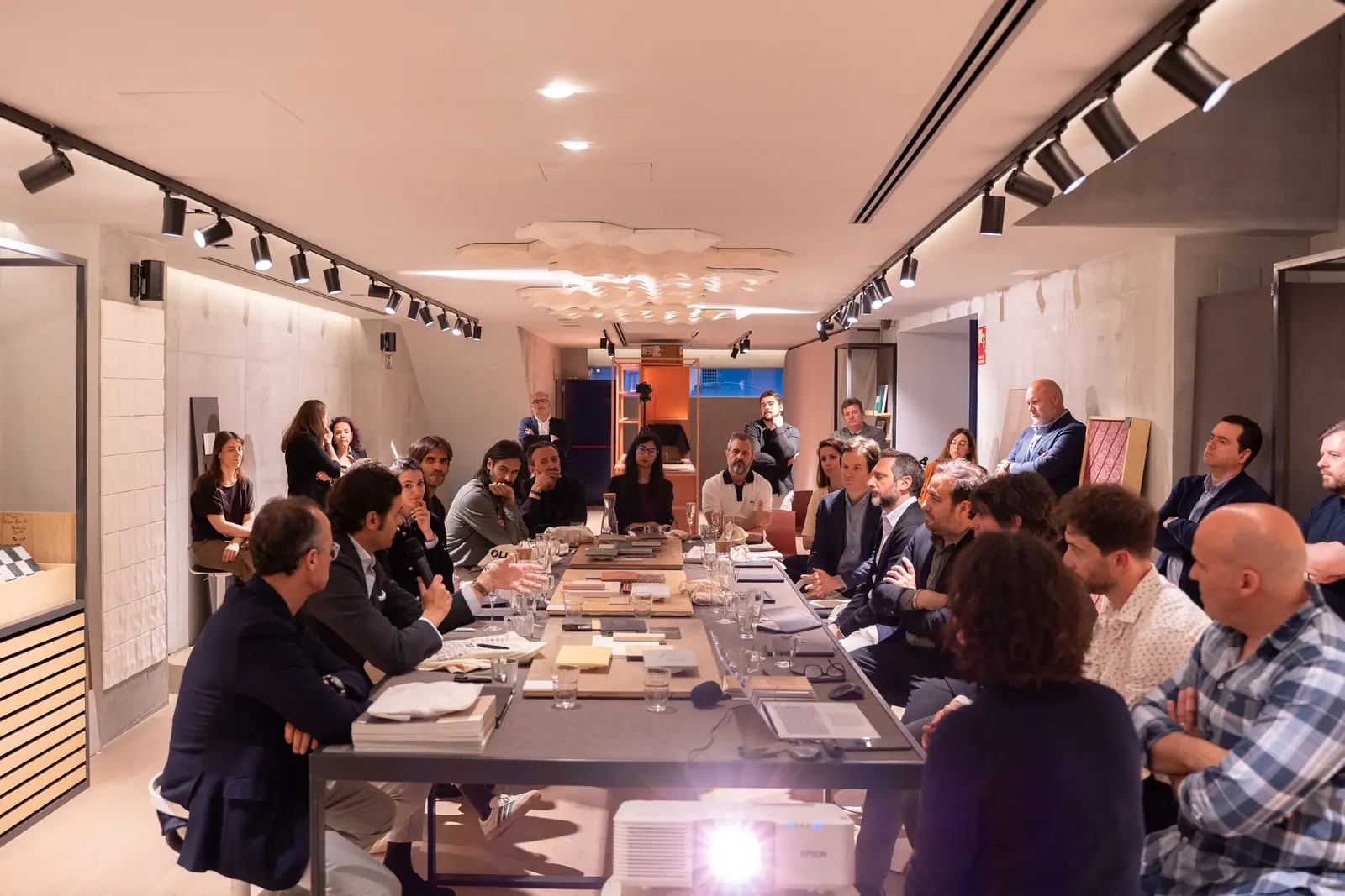 Estudios de arquitectura reunidos en torno a una mesa de materiales en un Best Practices Matter