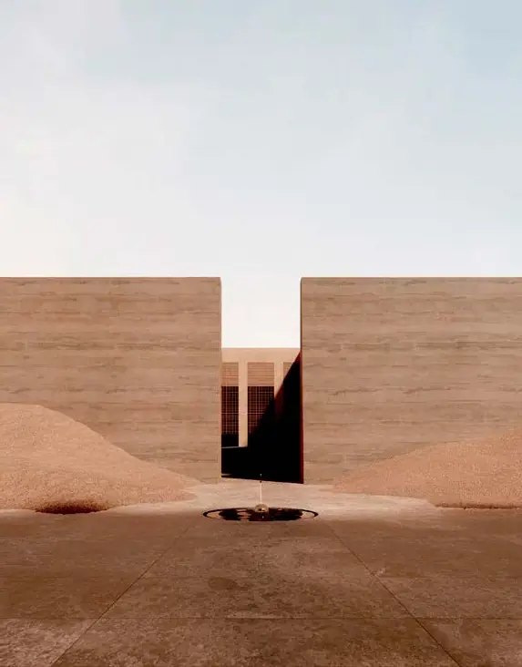 Dos muros de tono arena enmarcan un acceso entre montículos de arena del desierto