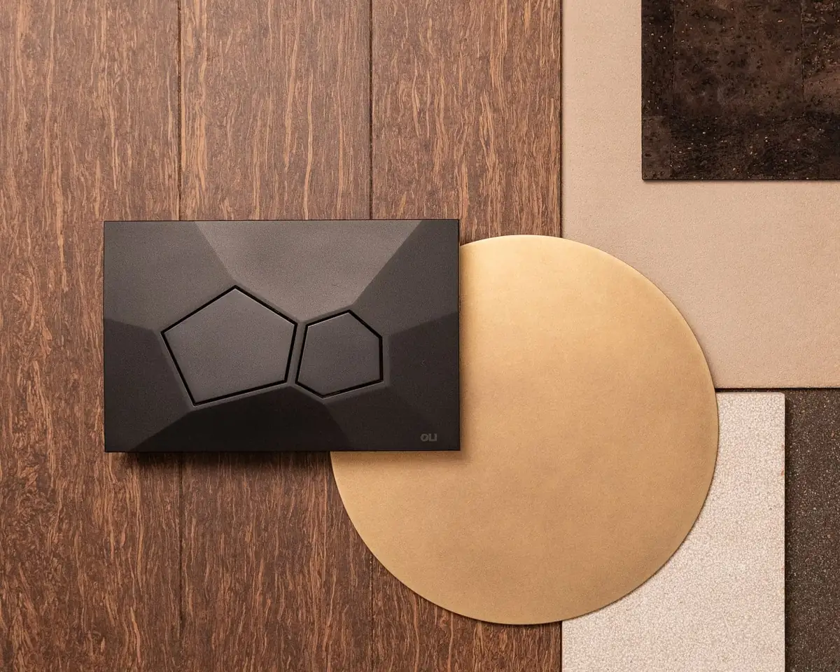 Pulsador Voronoi negro sobre una composición de madera, metal dorado y piedra