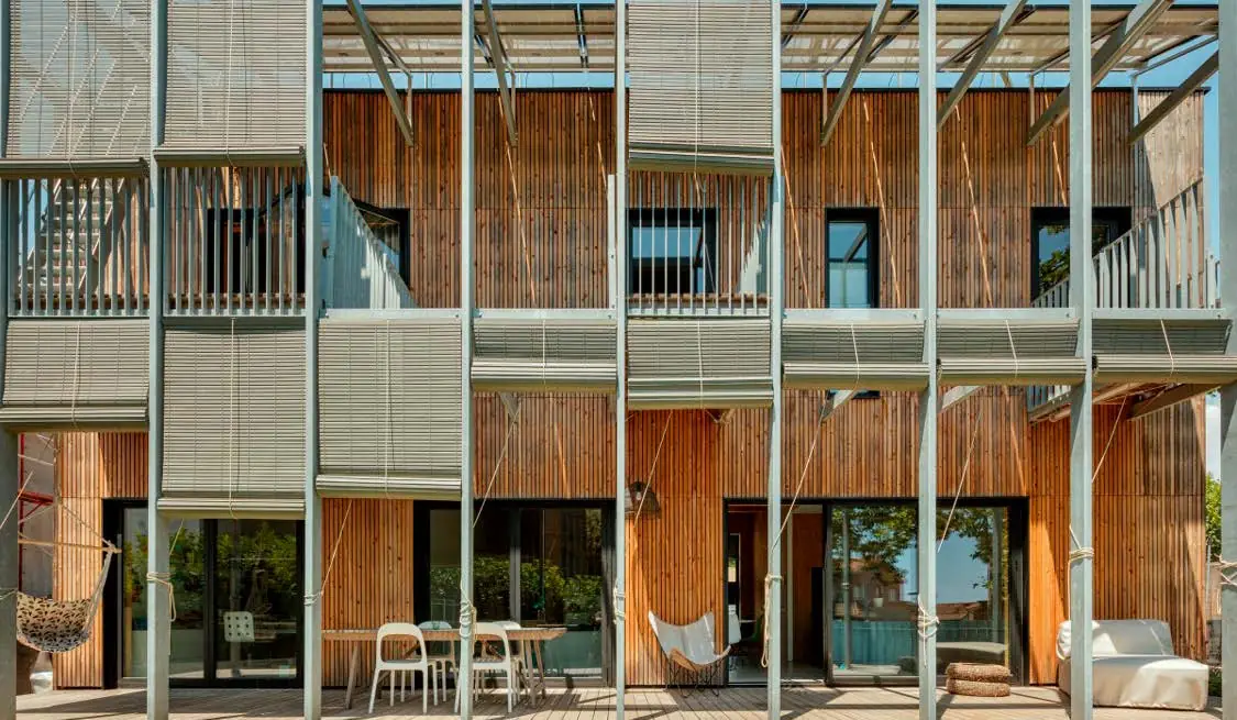 Fachada con balcones, persianas enrollables de madera y estructura metálica ligera