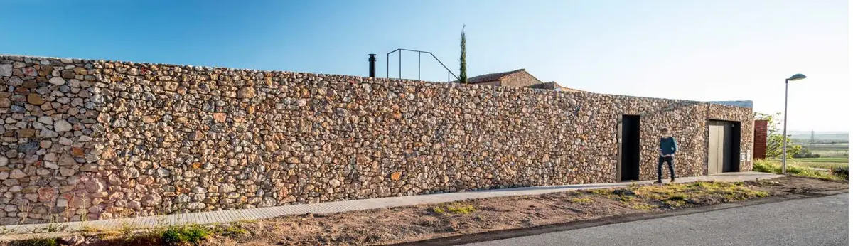 Largo muro de piedra de la casa AA paralelo a la carretera