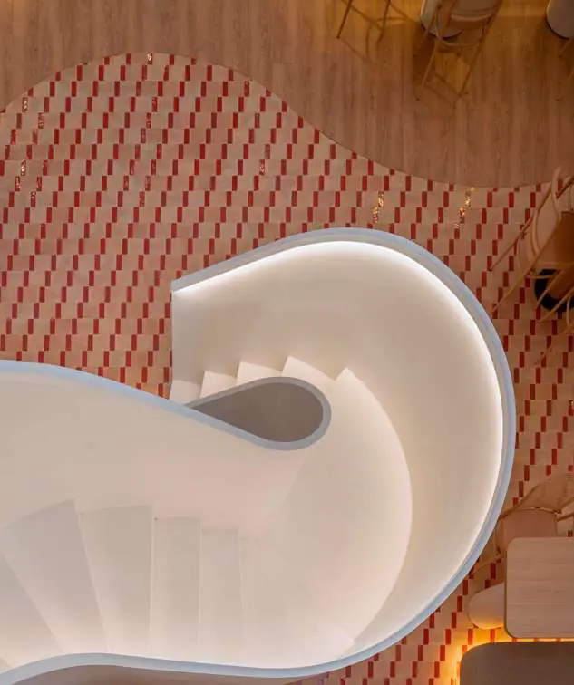 Escalera escultórica blanca de Juno House vista desde arriba sobre un pavimento de baldosas
