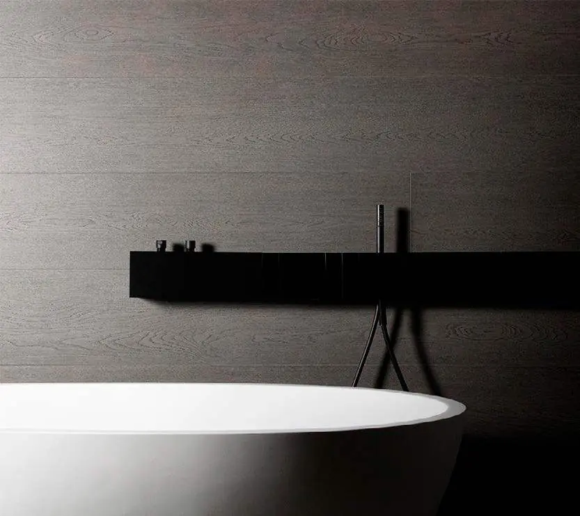 Baño con revestimiento oscuro de textura de madera, encimera negra y bañera exenta blanca