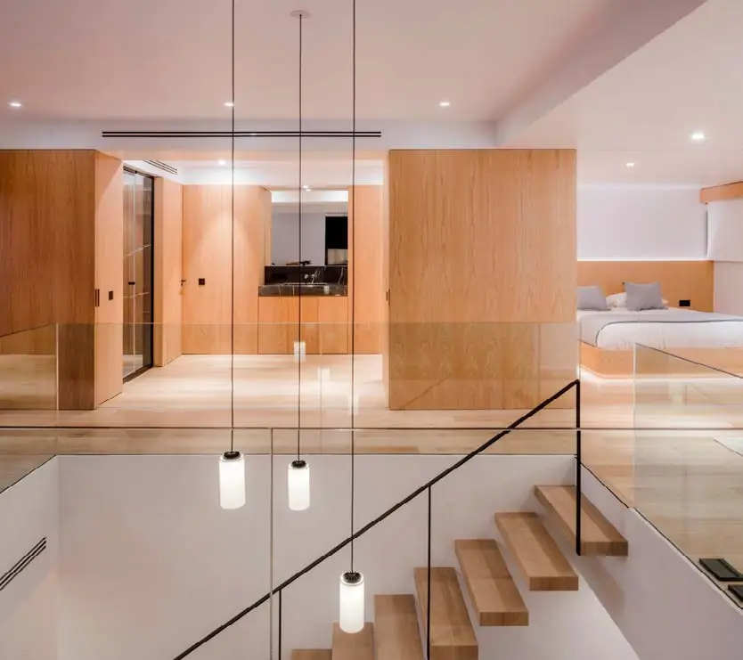 Interior de vivienda con suelo y carpinterías de roble, escalera ligera y lámparas colgantes