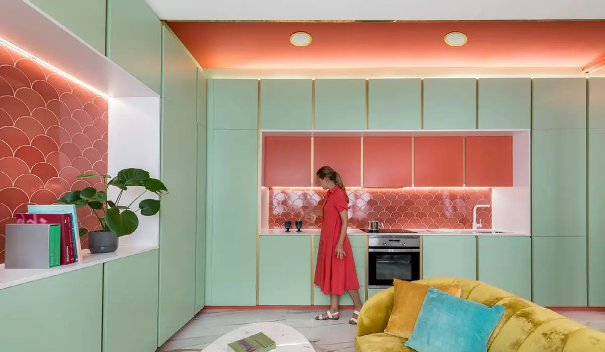 Vivienda con armarios color menta, nichos alicatados con escamas coral y una persona en la cocina