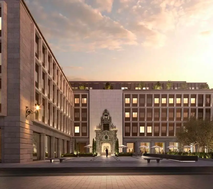 Fachada de piedra de un edificio racionalista con portada barroca iluminada al atardecer
