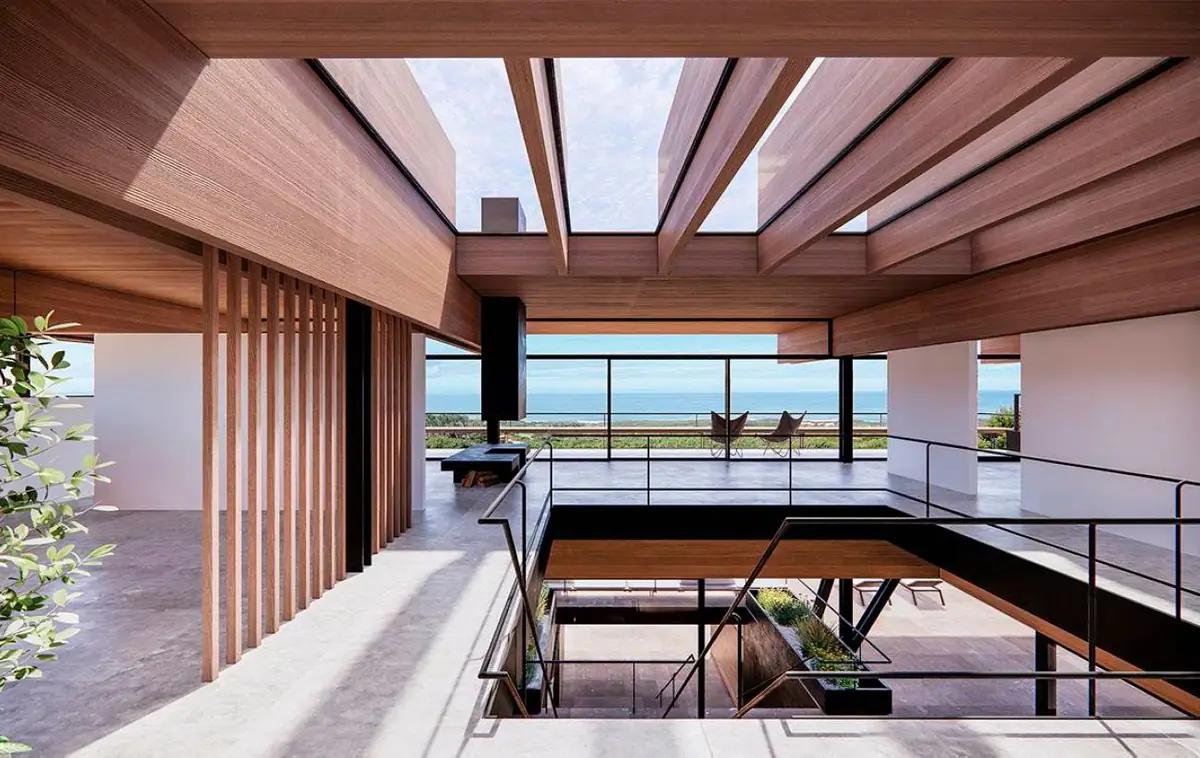 Interior a doble altura con vigas de madera, lucernarios y vistas al océano