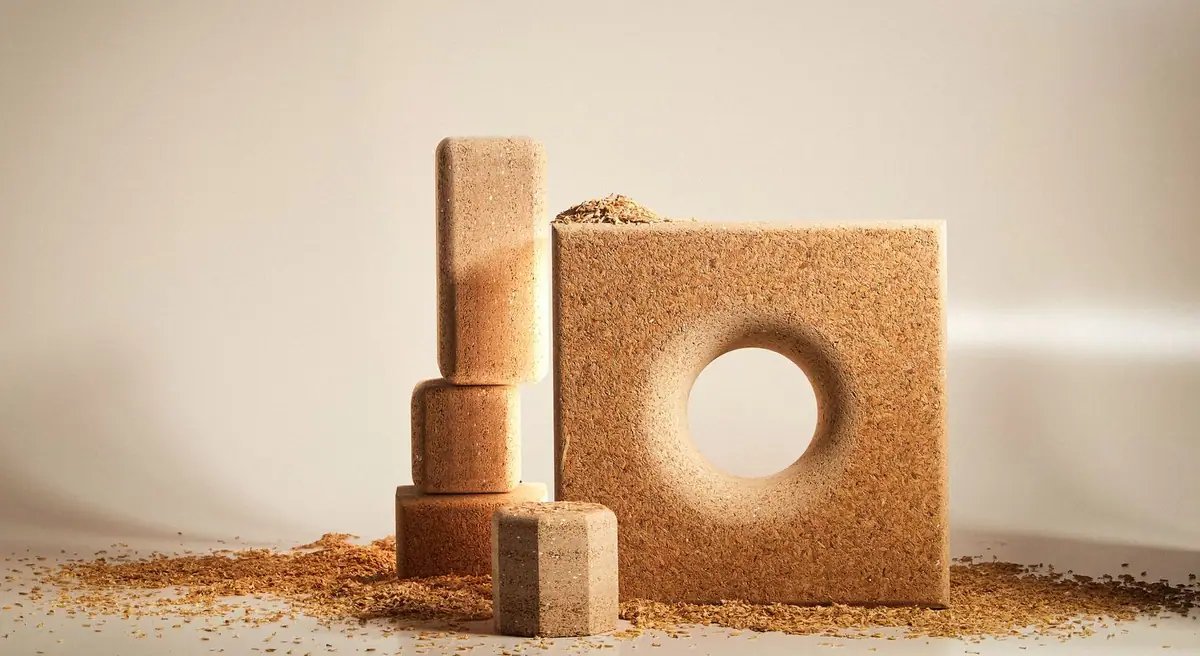 Bloques y un panel con un orificio circular de tablero de cascarilla de arroz, rodeados de cascarilla suelta