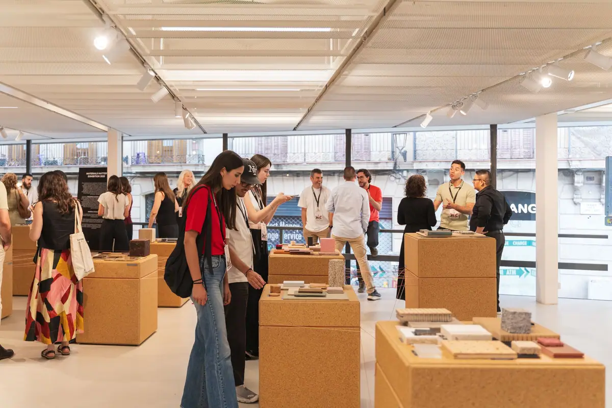 Visitantes observan muestras de materiales sobre tótems de tablero de cascarilla de arroz en una sala diáfana