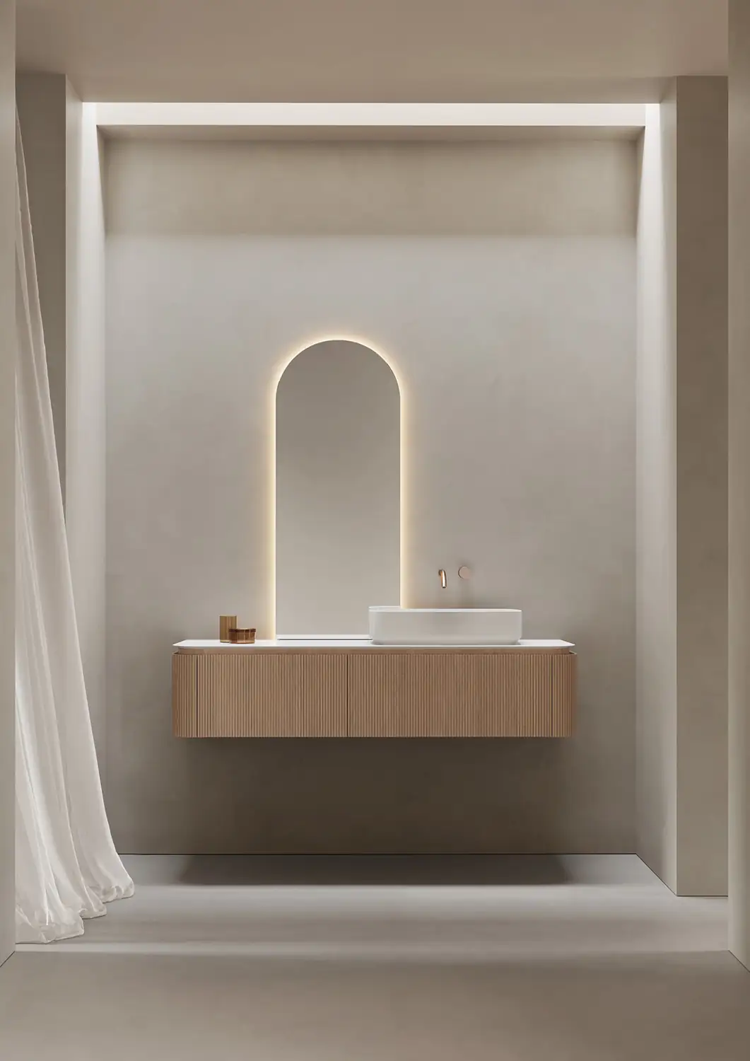 Mueble suspendido de madera clara acanalada con lavabo blanco sobre encimera y espejo en arco iluminado por detrás