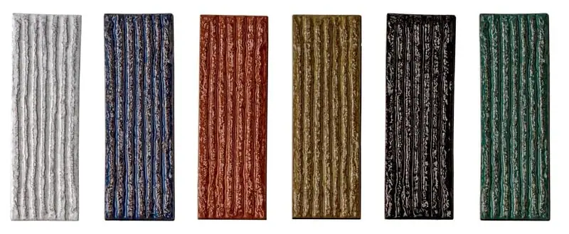 Seis piezas cerámicas alargadas con relieve de líneas verticales y esmalte brillante en blanco, azul, terracota, ocre, negro y verde.