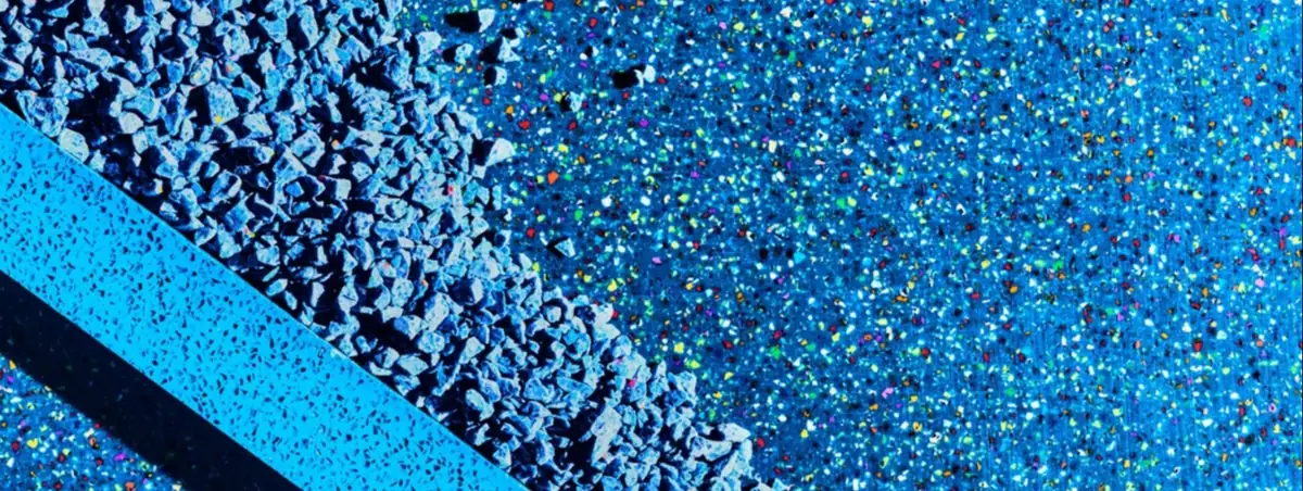 Granulado de plástico azul junto a una placa azul de superficie sólida con acabado moteado
