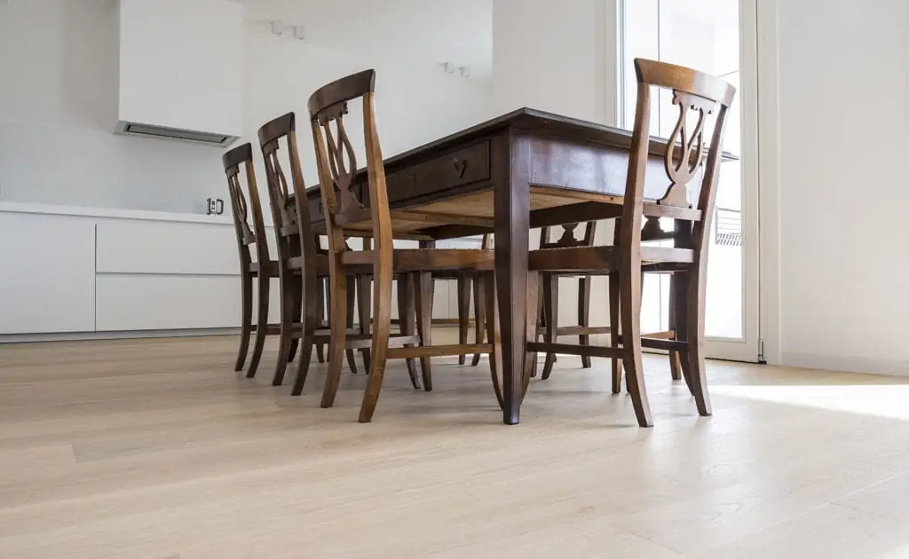 Comedor con mesa y sillas de madera oscura sobre un suelo de tablas anchas de roble muy claro
