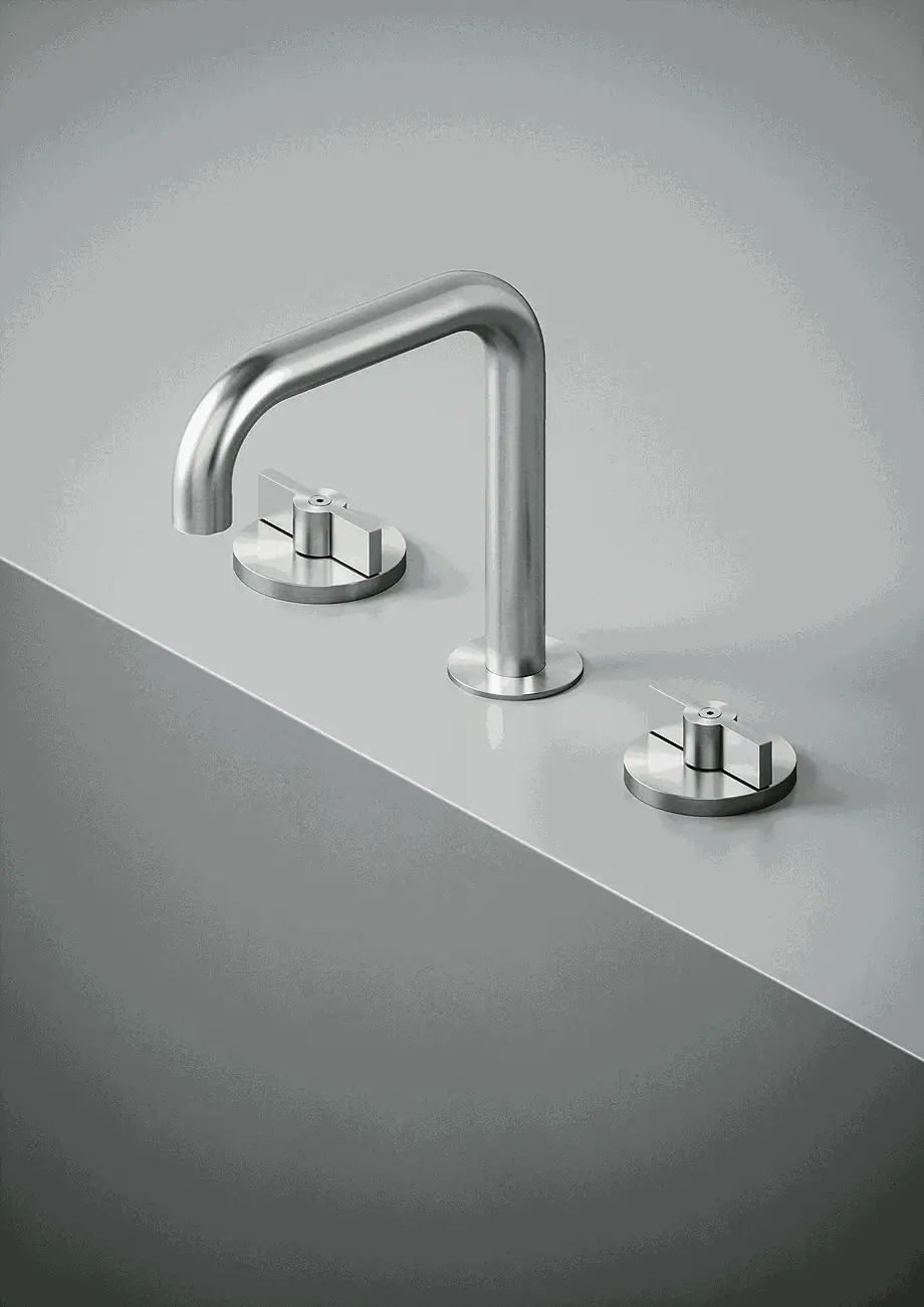 Grifería de lavabo de repisa de acero con caño curvo y dos mandos circulares sobre una encimera gris