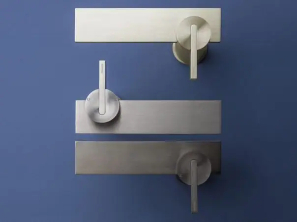 Tres mezcladores murales DOT316 con placa rectangular y mando de palanca, en tres tonos de acero sobre fondo azul