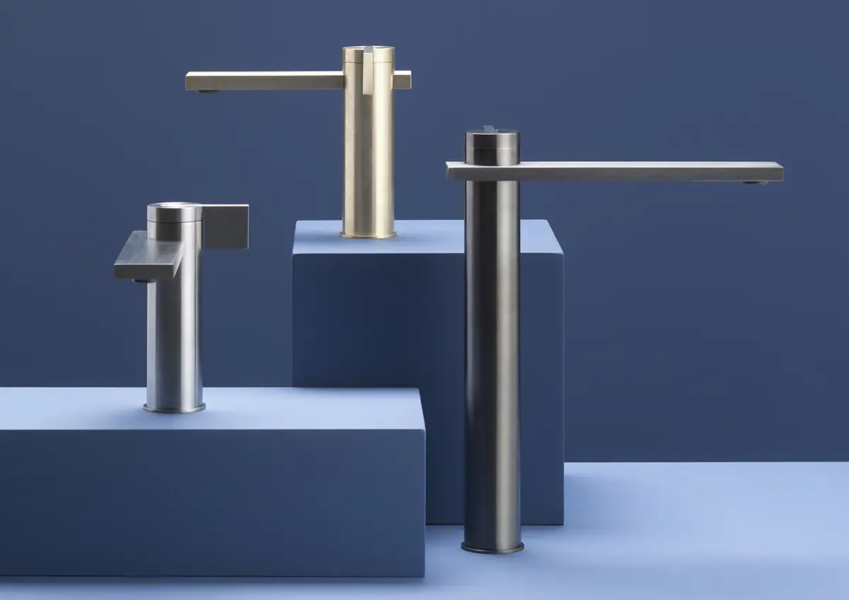 Tres mezcladores de lavabo DOT316 de distintas alturas y acabados sobre peanas azules