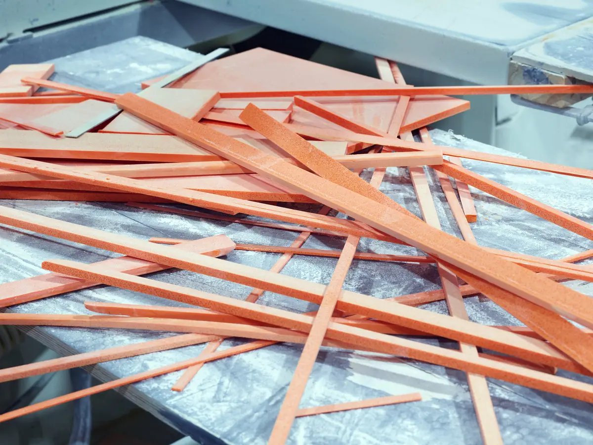 Tiras y recortes de superficie sólida de color salmón amontonados sobre una mesa de taller