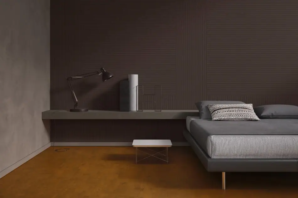 Dormitorio con la pared revestida de placas de corcho marrón oscuro con finas líneas horizontales en relieve y suelo en tono miel