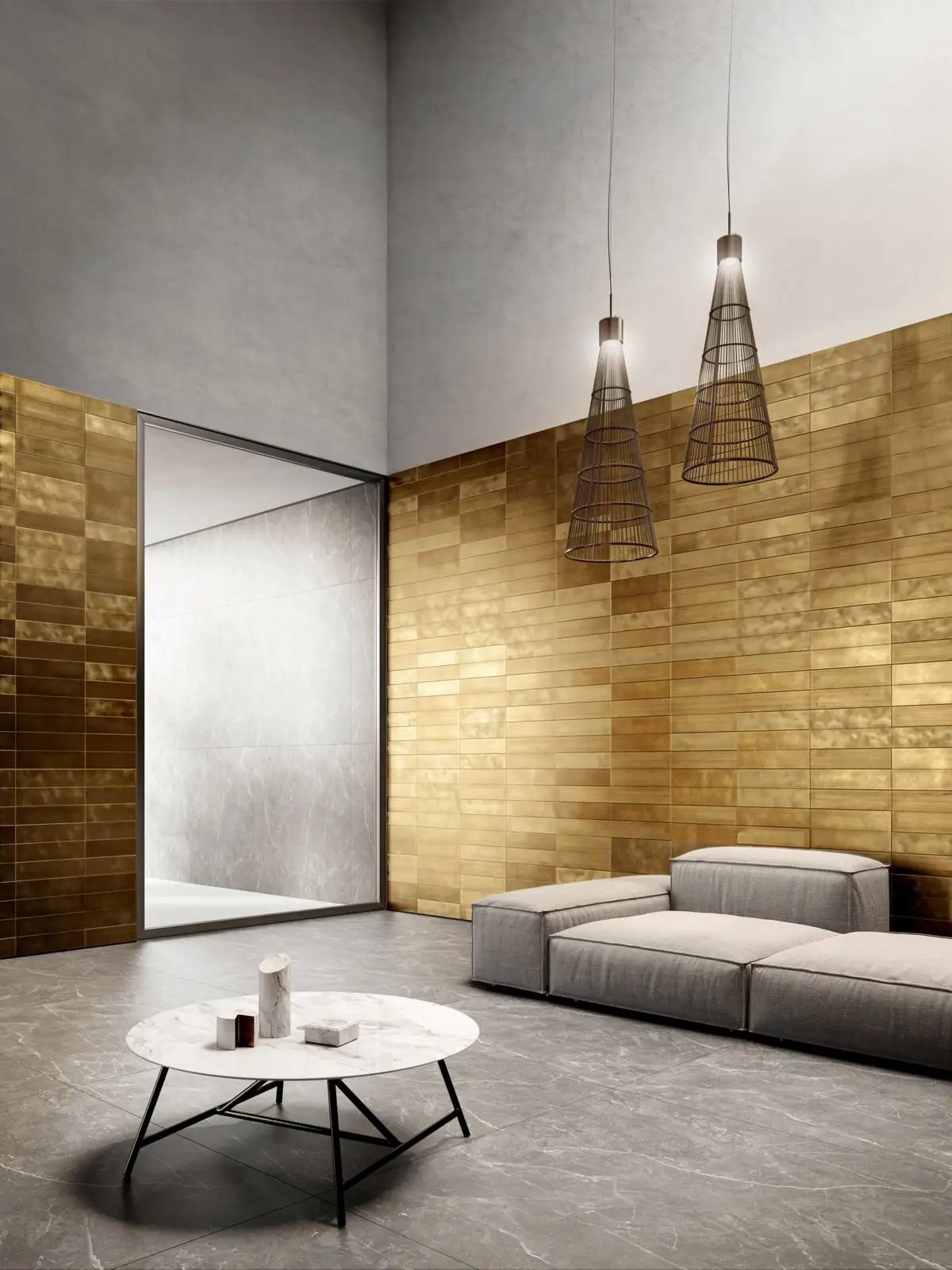 Salón de doble altura con dos paredes revestidas con piezas rectangulares de latón de distintos tonos y un sofá gris