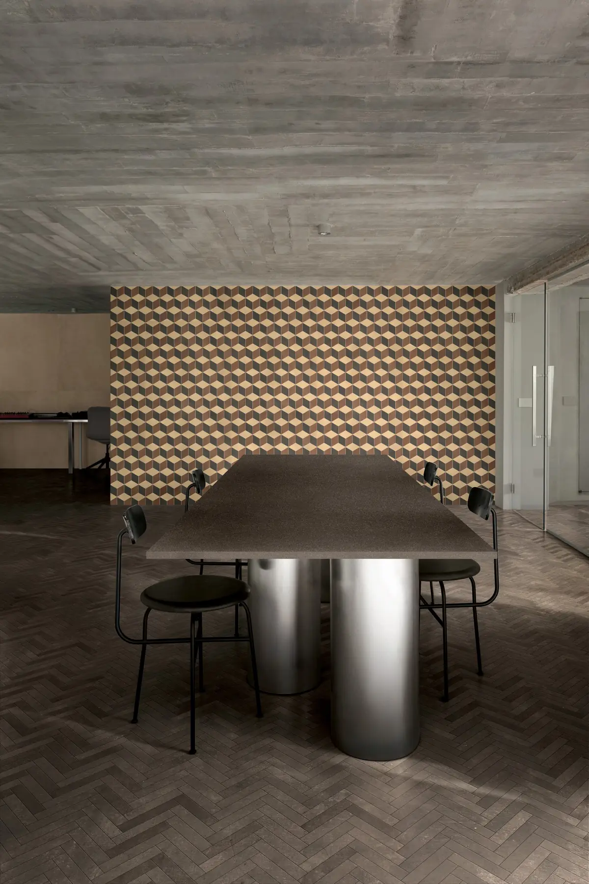 Comedor con suelo oscuro en espiga y pared revestida con un dibujo de cubos en tonos tierra