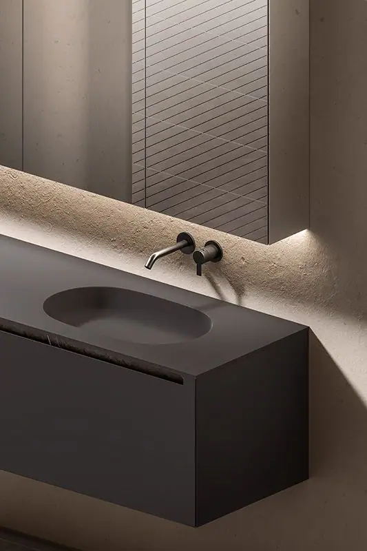 Detalle de un mueble de lavabo suspendido oscuro con lavabo integrado ovalado, uñero bajo la encimera y grifería mural