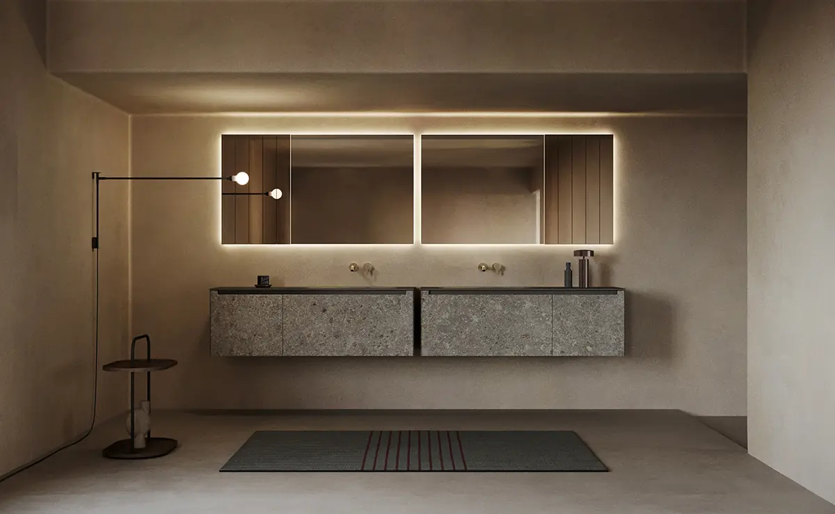 Dos muebles de lavabo suspendidos con frentes de aspecto pétreo gris y encimera negra, bajo espejos con luz perimetral