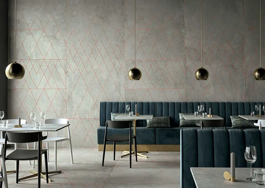 Restaurante con banco tapizado azul y pared de porcelánico gris efecto cemento con decoración de líneas geométricas