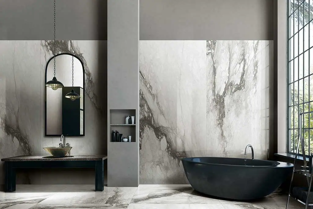 Baño con bañera negra y paredes y suelo de porcelánico blanco efecto mármol con vetas grises