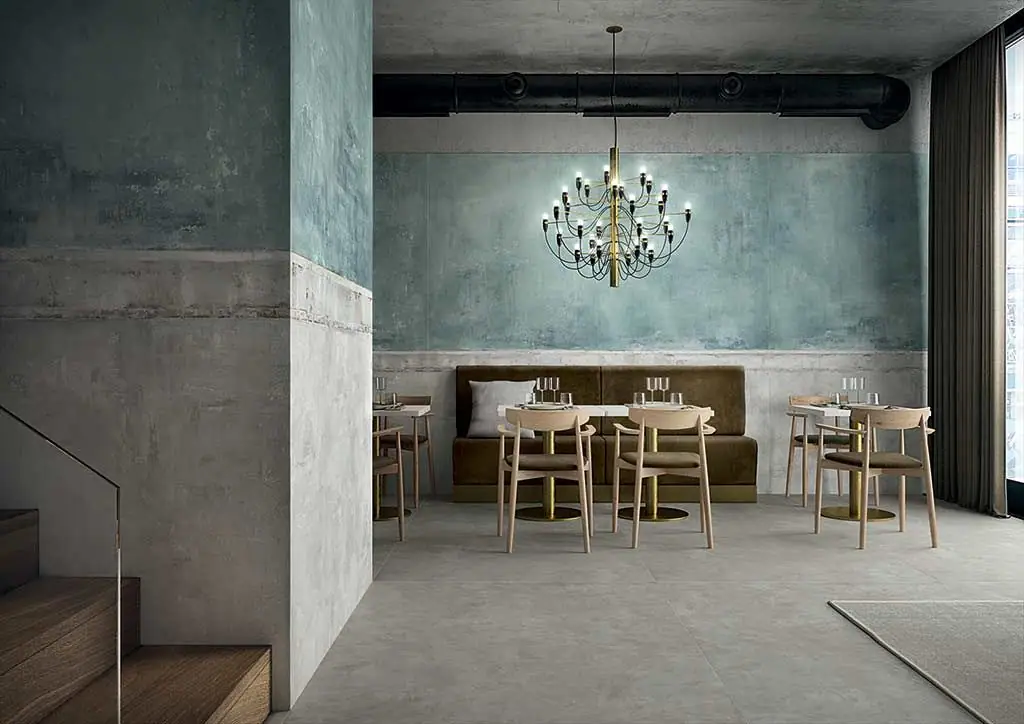 Restaurante con paredes revestidas de porcelánico en tonos verdes y azulados que imita revoques envejecidos