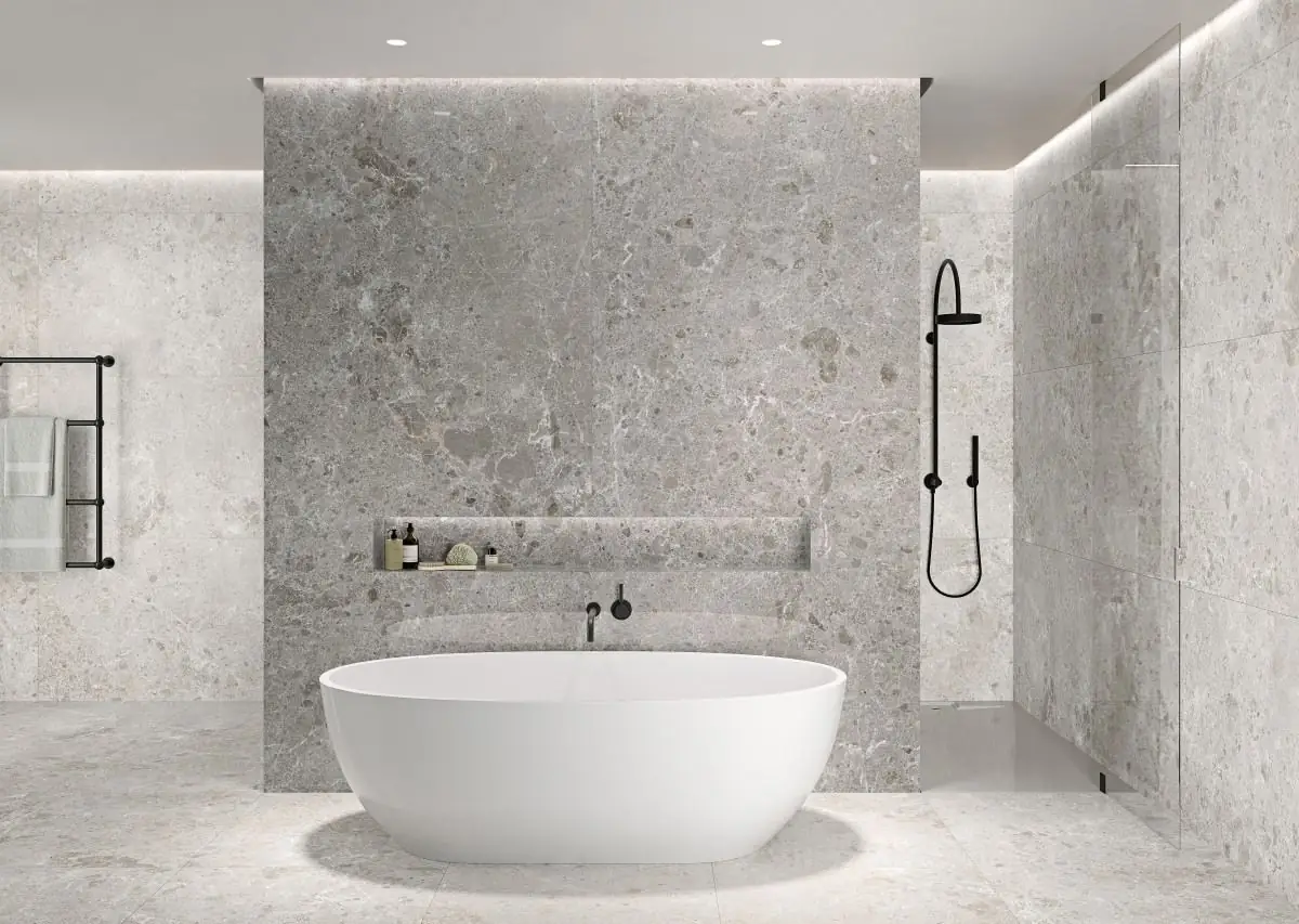 Baño con bañera exenta blanca y paredes y suelo revestidos de porcelánico gris efecto piedra en placas de gran formato